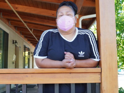 Photo of Clarice leaning against a rail wearing a mask.