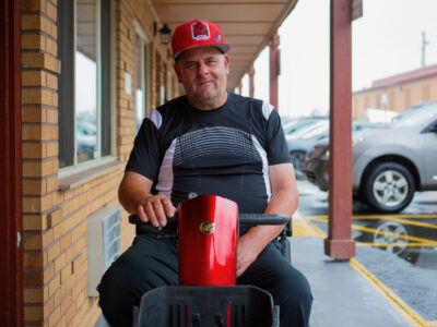 Man on a mobility scooter outside of a building.