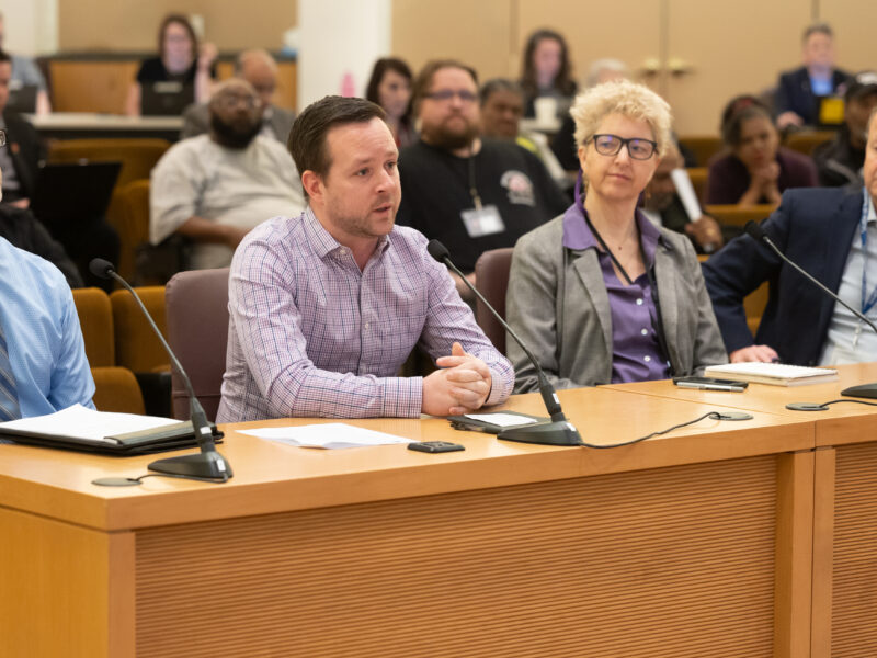 Four presenters from the Homeless Services Department sit at the dais in the boardroom.