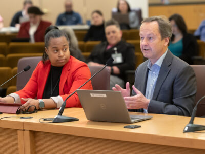 Antoinette Payne and Dan Field sit at the dais in the Multnomah County board room