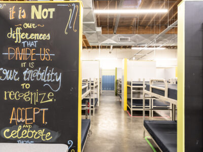 A chalk wall with a quote in front of a room full of bunk beds.