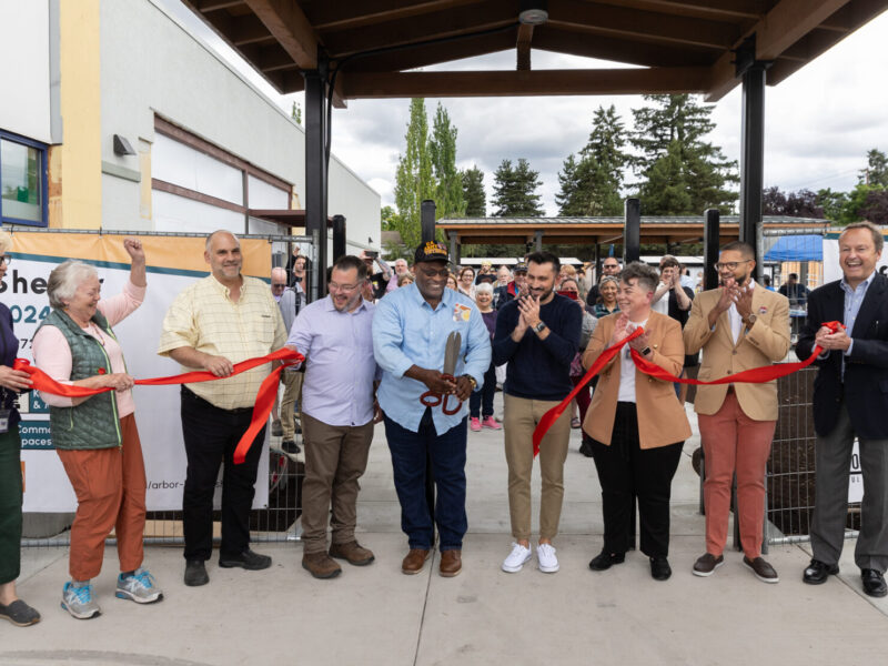 Large group cuts ribbon outside shelter