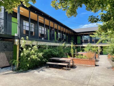Exterior of modern-looking motel with outdoor patio area.