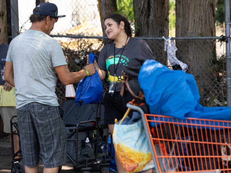 Cultivate Initiatives street outreach worker hands someone supplies.